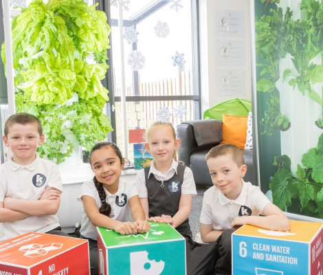 Image of children sat next to boxes printed with the UN's Sustainable Development Goals for Rethink Food project